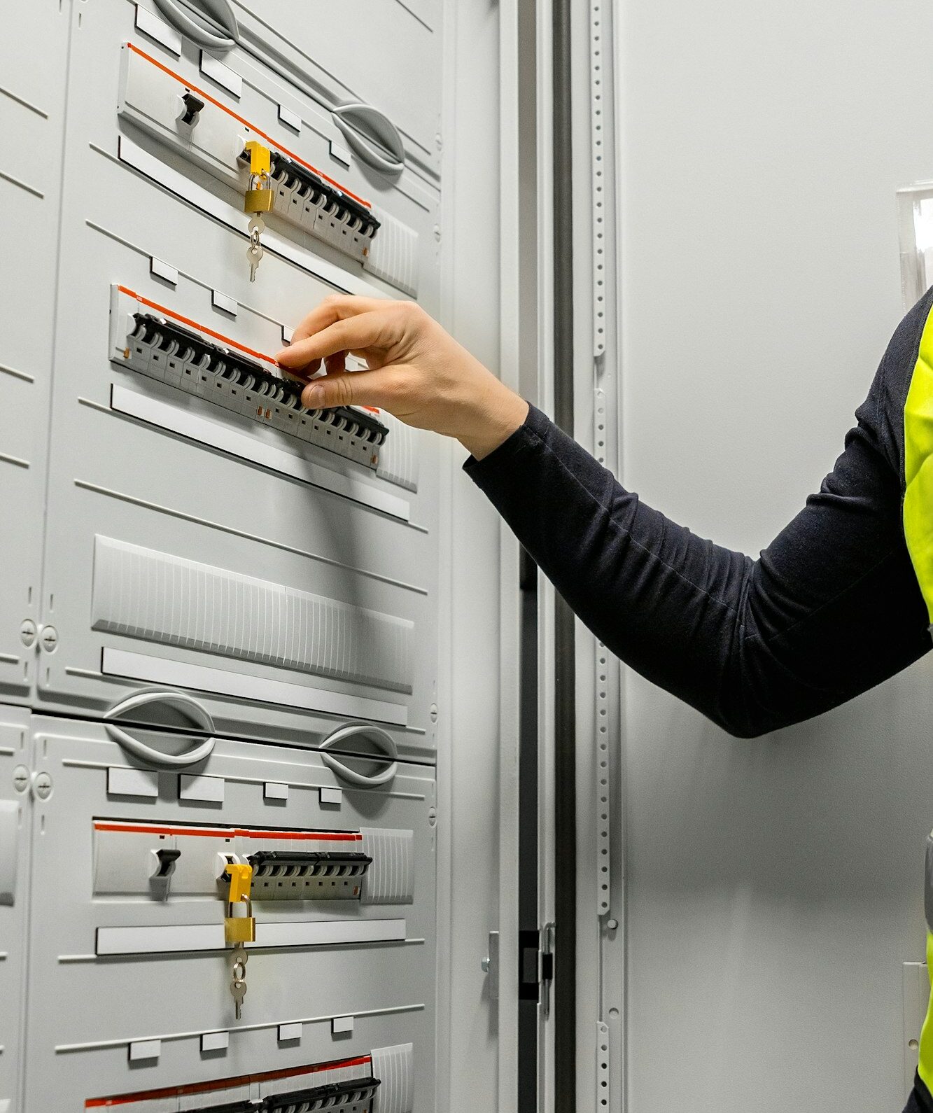 Male Electrician Checking Electric Fuse Board In Server Room