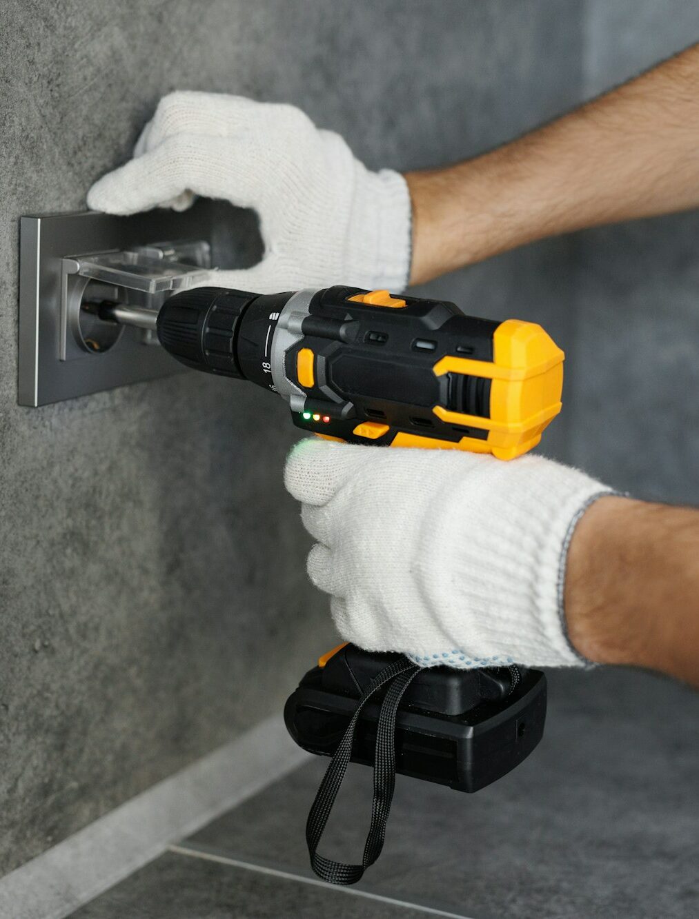 Man screws a bolt when installing an outlet in the kitchen. Electric screwdriver close-up.