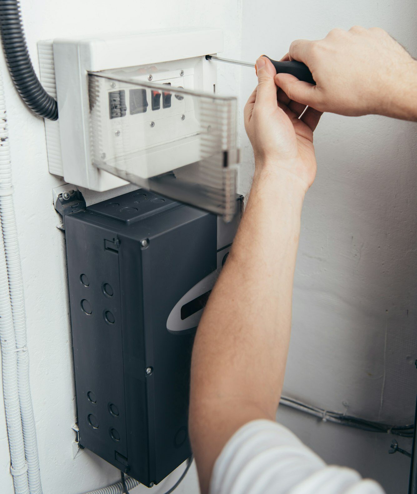 partial view of male electrician repairing electrical box by screwdriver